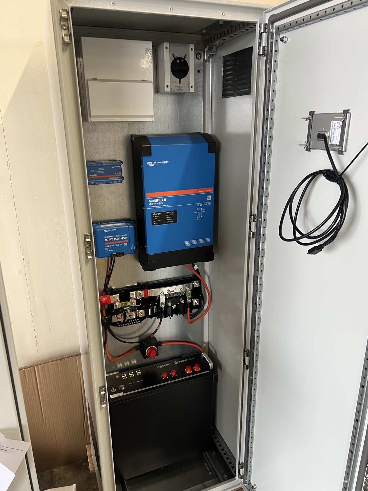 Waterproof steel off-grid power cabinet housing a Victron MultiPlus-II inverter, SmartSolar charge controller, Cerbo GX monitor and Pylontech battery storage, built for a cabin near Thurso